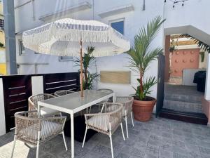 una mesa blanca con sillas y una sombrilla en el patio en La Mona Suites - Cozy 1 BR with Full Kitchen, en San Juan
