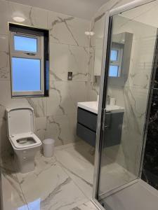 La salle de bains blanche est pourvue de toilettes et d'une fenêtre. dans l'établissement Potters Hideout- Warner Bros Studios and London, à Watford