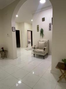 ein Wohnzimmer mit einem Stuhl und einem großen Fliesenboden in der Unterkunft شقة مفروشة حي الصفا in Al Wajh