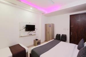 ニューデリーにあるHotel Red Velvet suitesのベッドルーム1室(ベッド1台、壁掛けテレビ付)