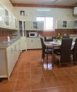 eine Küche mit weißen Schränken sowie einem Tisch und Stühlen in der Unterkunft شقة مفروشة حي الصفا in Al Wajh