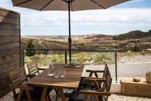 a wooden table with an umbrella on a patio at maresoul - Ferienapartment mar in Raposeira