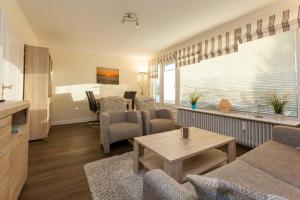 ein Wohnzimmer mit einem Sofa, Stühlen und einem Tisch in der Unterkunft Sylter Sonne, Alt Westerland in Westerland
