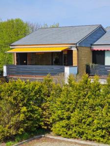 ein Haus mit einer Veranda und einigen Büschen in der Unterkunft Sylter Sonne, Alt Westerland in Westerland