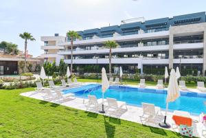 a resort with a swimming pool and chairs and a building at Apartment AMAZING in Orihuela