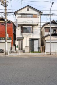 een wit huis aan de kant van een straat bij The year 2024 is in the discount period! Near USJ in Osaka