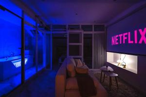 ein Wohnzimmer mit Sofa und Neonschild in der Unterkunft Oasis Chic - Spa privé & Cinéma in Reims