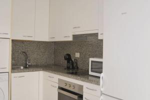 Una cocina con gabinetes blancos, un fregadero y un microondas. en Apartamento Lapa, en Tías