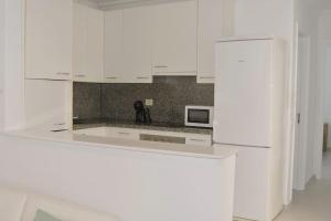 cocina blanca con armarios blancos y microondas en Apartamento Lapa, en Tías
