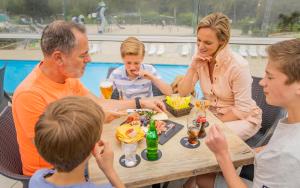 a group of people sitting around a table at Ardennen Camping Bertrix in Bertrix