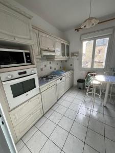 eine Küche mit weißen Schränken und weißen Fliesenböden in der Unterkunft Chambre entre plage et centre ville dans maison avec jardin in Le Havre