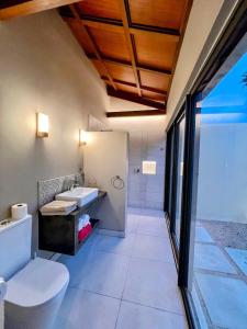 La salle de bains est pourvue de toilettes blanches et d'un lavabo. dans l'établissement Lakaz Kannell - Room 2 - Turtle Lodge, secluded outside bath & shower infinity pool, à Cap Malheureux