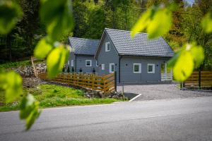 una casa gris con una valla de madera frente a una carretera en Domki u Sosny en Brenna
