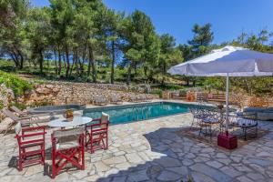 un patio con mesa, sillas y sombrilla en Villa Ira, en Agios Leon