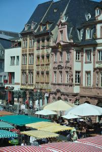 eine Gruppe von Tischen mit Sonnenschirmen vor den Gebäuden in der Unterkunft Ferienwohnung "Schön Wohnen in Mainz" in Mainz