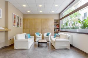 a living room with two white chairs and a table at Hotel Domomea in Alghero