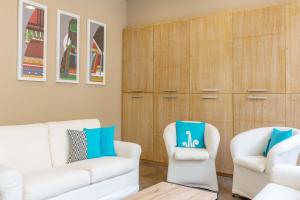 a living room with two white chairs and a wooden cabinet at Hotel Domomea in Alghero