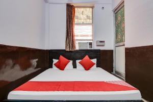 a bedroom with a bed with red pillows and a window at OYO Flagship Hotel Golden Inn in Bhiwadi