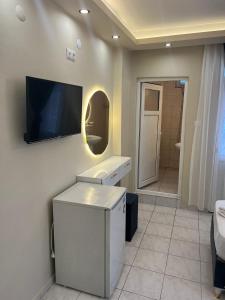 baño con TV en la pared y lavamanos en Almir Otel, en Erdemli