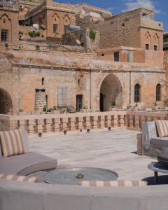 un patio extérieur avec une table et des chaises en face d'un bâtiment dans l'établissement Mirsoum Han, à Mardin
