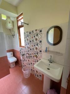 een badkamer met een wastafel, een spiegel en een toilet bij OYO Home Urvi Griham in Gangtok