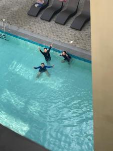 three people swimming in a swimming pool at Stanford Suites 3, staycation near Nuvali, located in Silang in Bayabasan