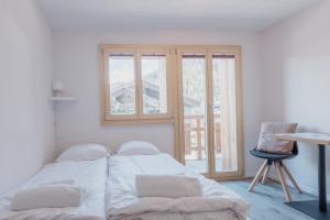 a white bedroom with a bed and a window at Chaleureux studio rénové à Grimentz in Grimentz