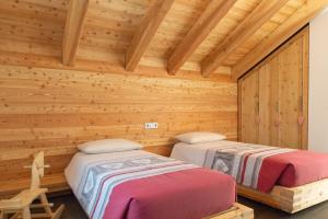 two beds in a room with wooden walls at Maso Stella in Castello Tesino