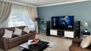 sala de estar con sofá y TV de pantalla plana en Nyasa Villa en Southgate