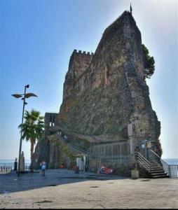 un bâtiment situé sur le côté d'une montagne à côté de l'océan dans l'établissement Casa della Vacanza a Catania - Acicastello, à Aci Castello