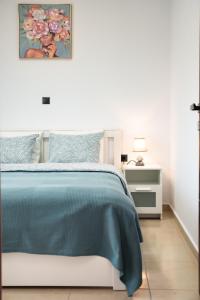 a white bedroom with a bed with a blue comforter at Valeria Apartament Cozy & Quiet in Kallithea Halkidikis