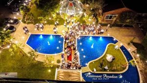 un grupo de personas de pie alrededor de una piscina por la noche en Hotel Paradise, en Fshati i Ri