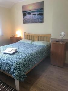 a bedroom with a bed with a table and a picture on the wall at Becontreelodge in Dagenham