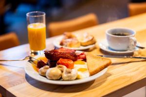 a breakfast plate of eggs sausage and toast and a cup of orange juice at Sandman Signature Glasgow Hotel in Glasgow