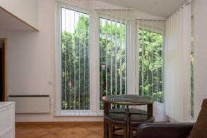 a living room with a table and two large windows at Palangos Saulegraza in Palanga