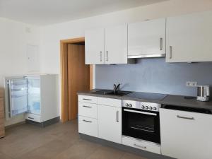 a kitchen with white cabinets and a stove top oven at Ferienwohnungen Weishaupt in Meckenbeuren