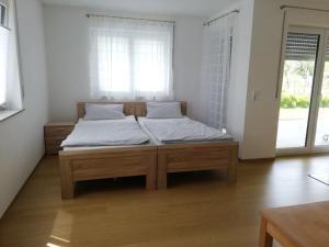 - une chambre avec un lit doté de draps blancs et une fenêtre dans l'établissement Ferienwohnungen Weishaupt, à Meckenbeuren