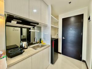 uma pequena cozinha com um lavatório e uma porta preta em New Comfort Studio at Central of Nagoya em Jodoh