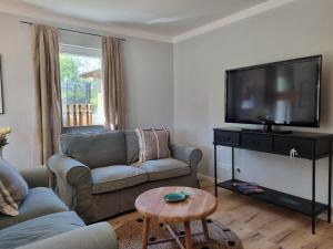 ein Wohnzimmer mit einem Sofa und einem Flachbild-TV in der Unterkunft Boutique Ferienhaus Chiemsee in Übersee