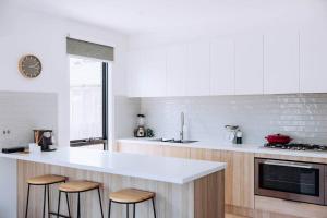 a kitchen with a white counter and stools in it at MODERN LUXE TOWNHOUSE / ROSEBUD in Rosebud