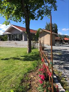 una casa con una valla y flores en el patio en Orkla Camping, en Orkanger
