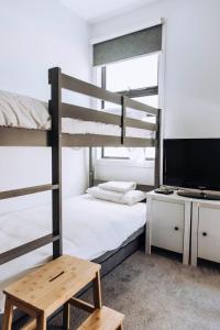 a bedroom with a bunk bed and a television at MODERN LUXE TOWNHOUSE / ROSEBUD in Rosebud