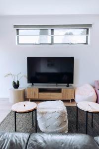 a living room with a flat screen tv and two stools at MODERN LUXE TOWNHOUSE / ROSEBUD in Rosebud
