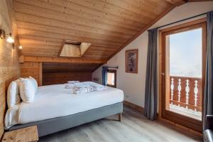 a bedroom with a bed in a wooden room with a window at Madame Vacances Chalet L'Arclusaz in Les Allues