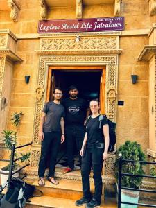 Explore Hostel Life Jaisalmer في جيلسامر: ثلاث رجال واقفين على درج مبنى