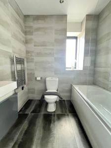 a bathroom with a white toilet and a bath tub at Luxury Norwich City Centre Apartment - Free Parking in Norwich