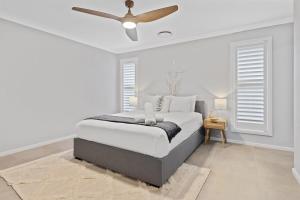 a white bedroom with a bed and a ceiling fan at Pineapple House - Furry Friends Welcome! in Cessnock