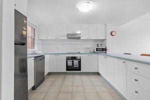 a large white kitchen with white cabinets and appliances at Bay Bliss - Coastal Villa in Nelson Bay