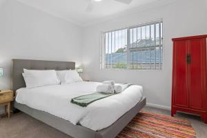 a bedroom with a large white bed with a red cabinet at Bay Bliss - Coastal Villa in Nelson Bay