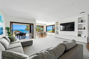 a living room with a couch and a television at WATERFRONT HOME WITH POOL / SHELLHARBOUR in Shellharbour